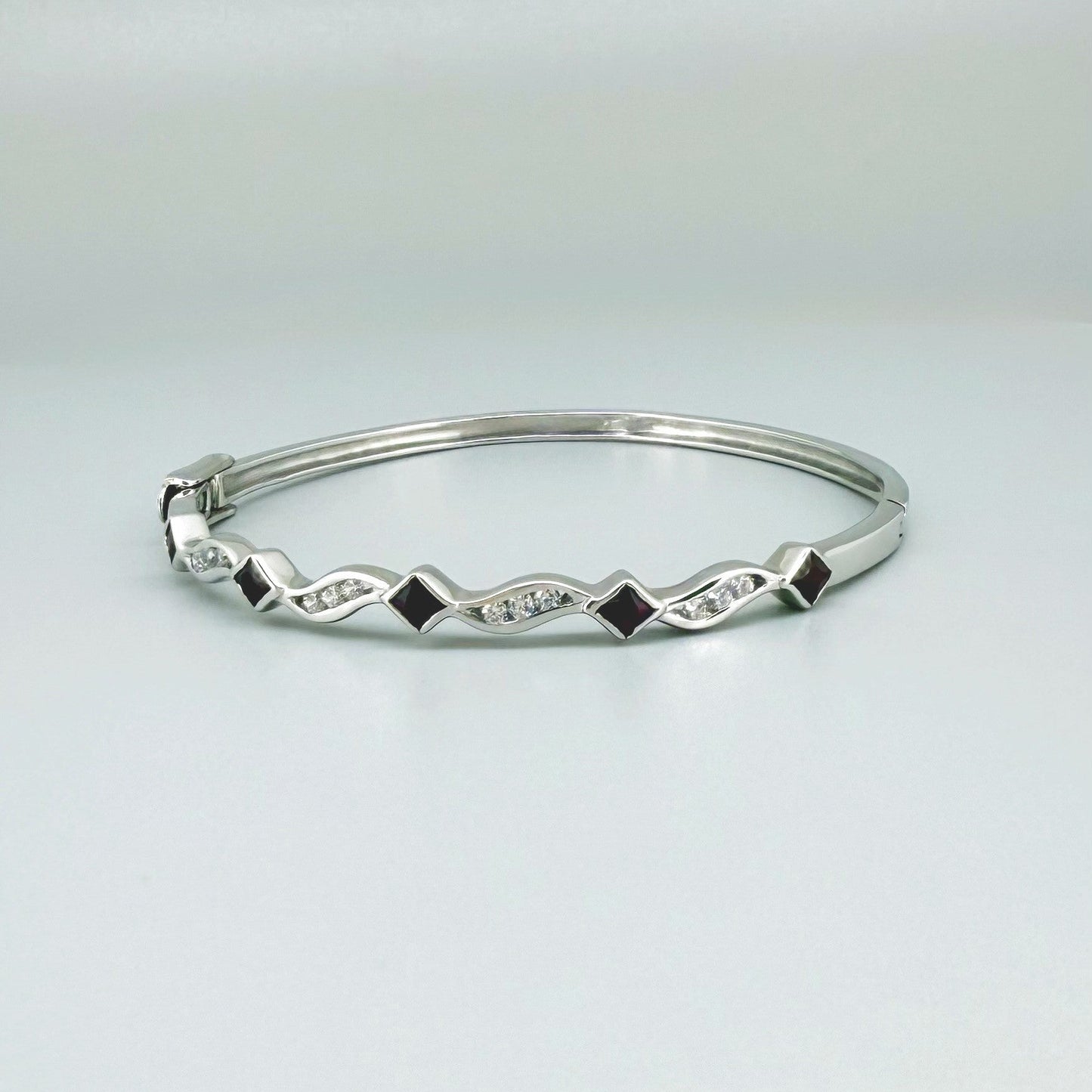 White gold plated silver bangle with natural rubies and cubic zirconia in a refined alternating design.