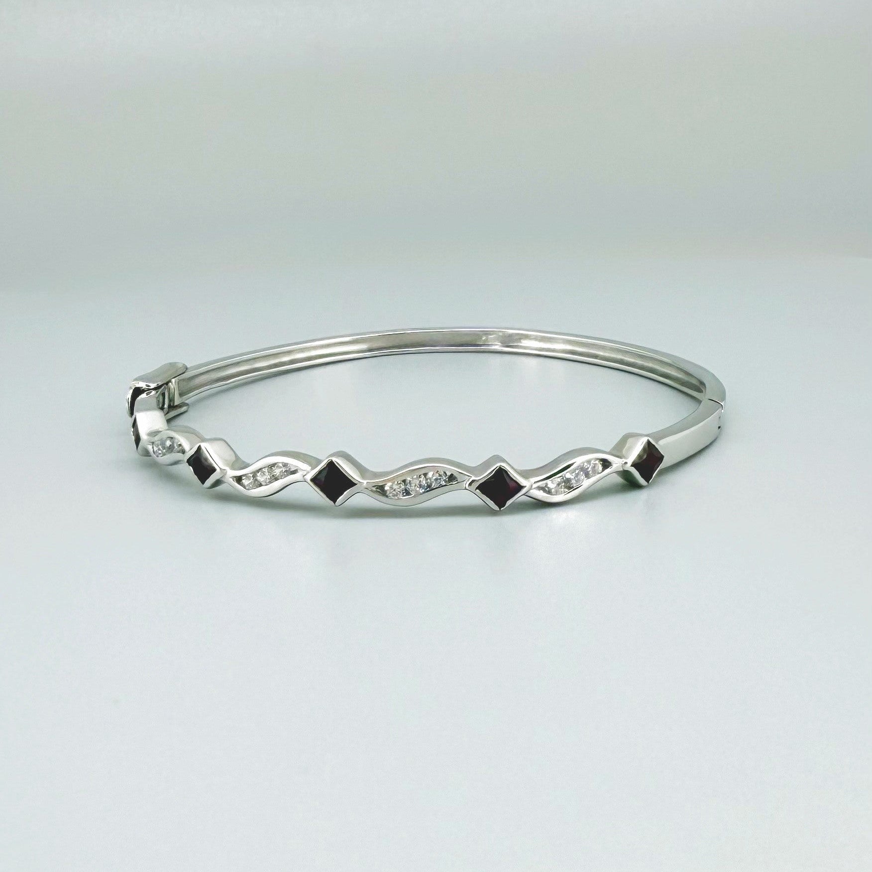 White gold plated silver bangle with natural rubies and cubic zirconia in a refined alternating design.