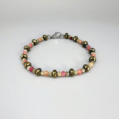 Faceted beaded bracelet with ruby, sapphire, emerald, and pyrite gemstones on neutral background