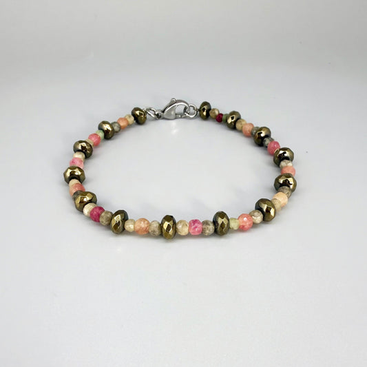 Faceted beaded bracelet with ruby, sapphire, emerald, and pyrite gemstones on neutral background