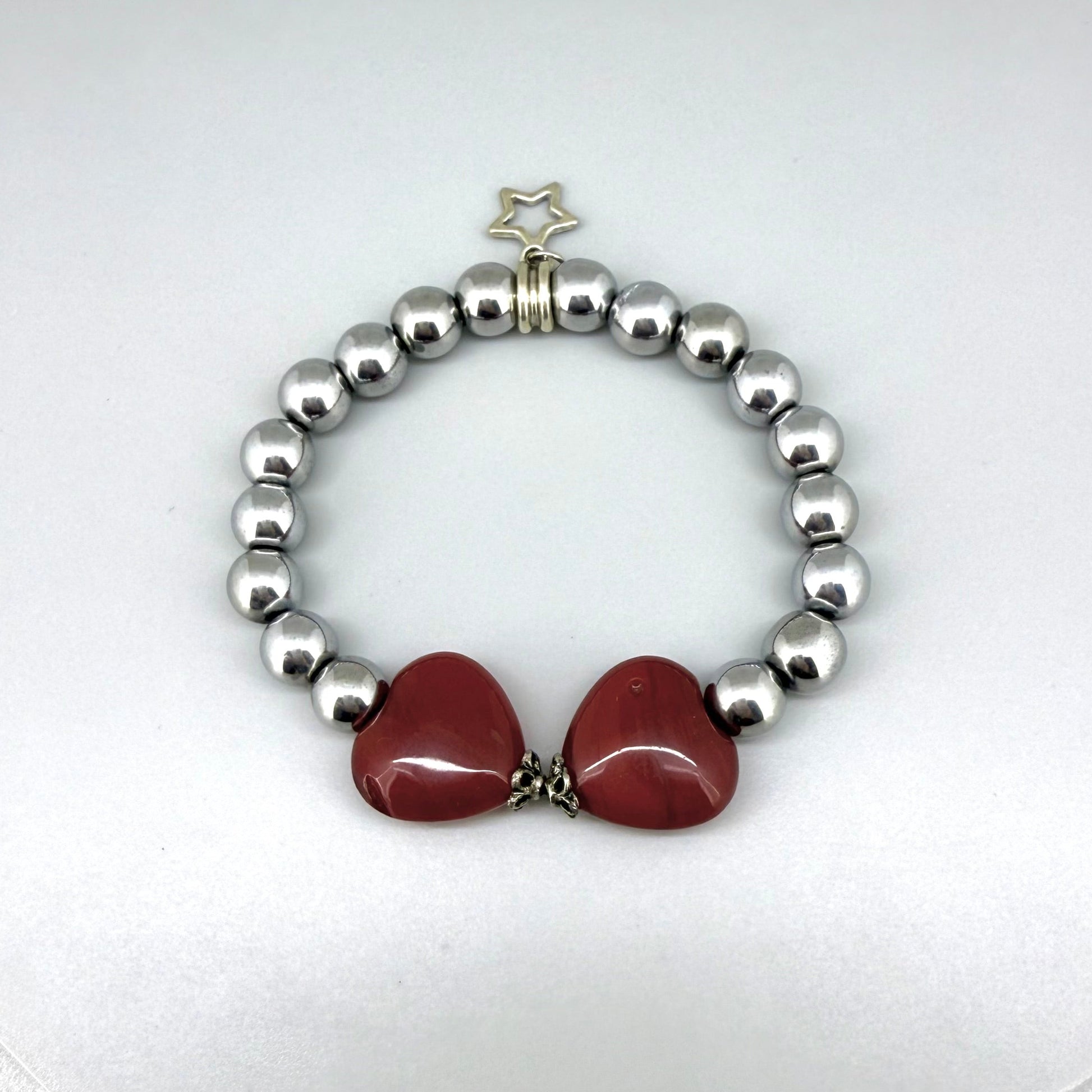 Silver hematite beaded bracelet, 18cm, metallic gemstone beads with two orange-red heart-shaped carnelian accents on elastic stretch band.
