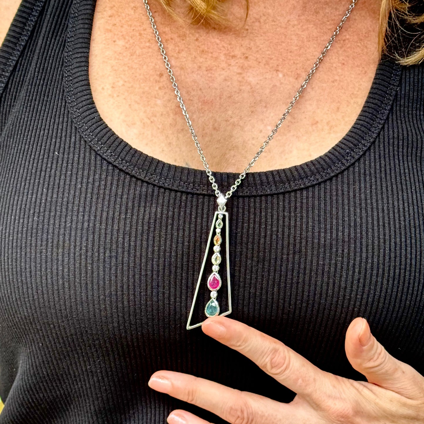 Handmade white gold plated silver pendant featuring 1.97 ct sapphires and 1.32 ct rubies in a modern geometric design with a freely moving gemstone strand.