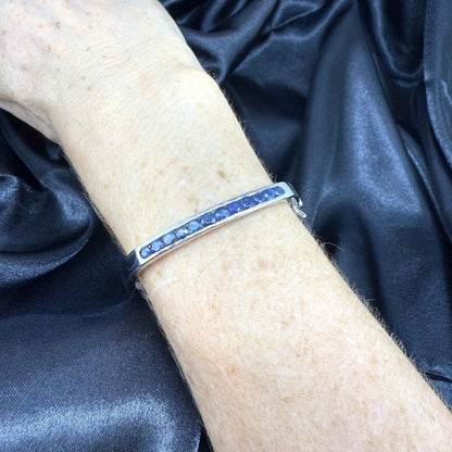 White gold plated silver bangle with natural blue sapphires in a sleek classic design.