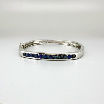 White gold plated silver bangle with natural blue sapphires in a sleek classic design.