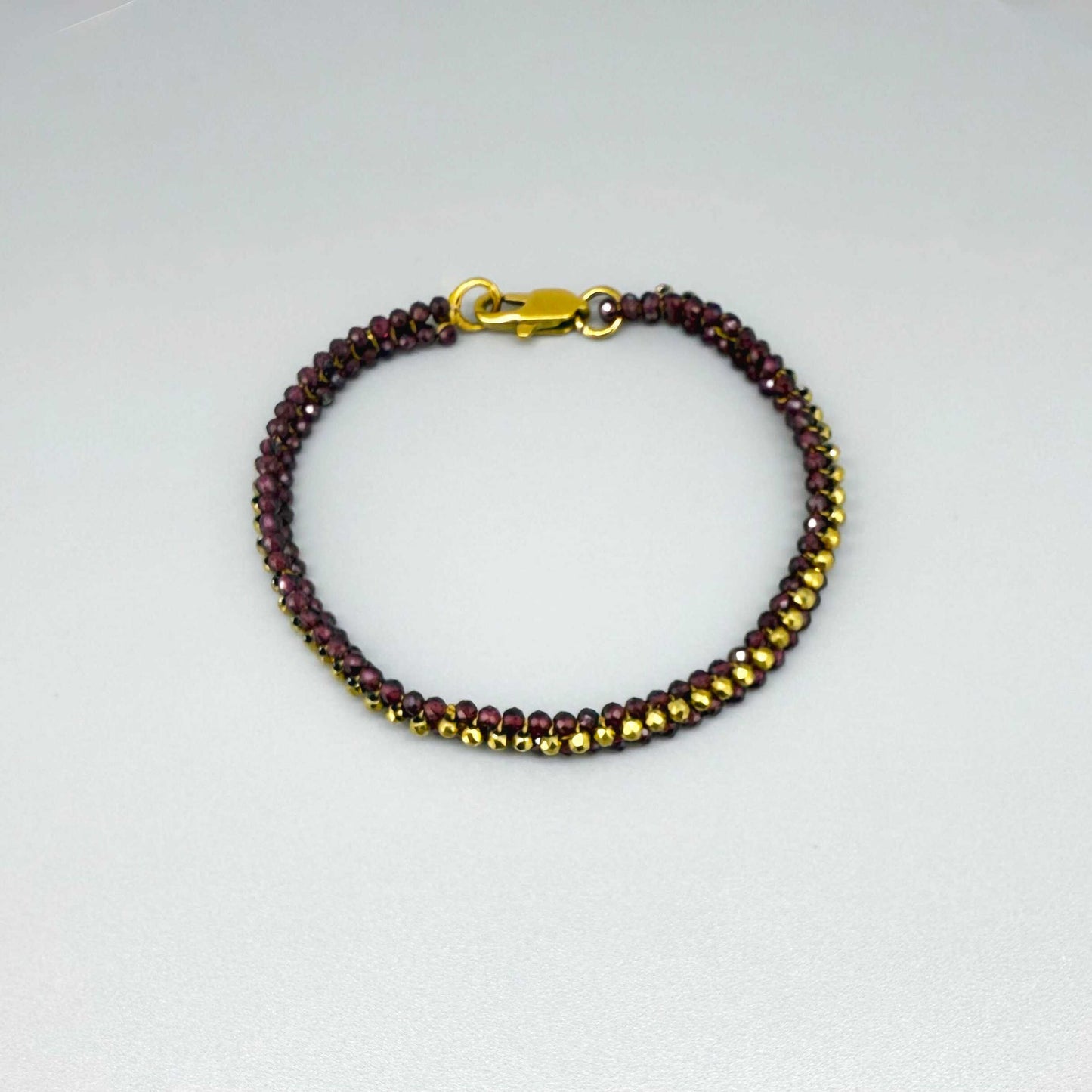 18 cm beaded bracelet made of wine-red garnet and gold-toned hematite with a lobster clasp, displayed on a light background.