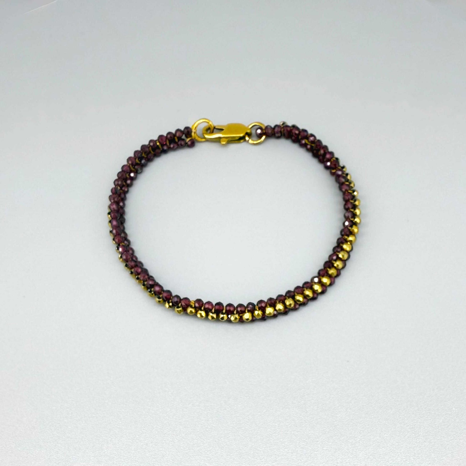 18 cm beaded bracelet made of wine-red garnet and gold-toned hematite with a lobster clasp, displayed on a light background.