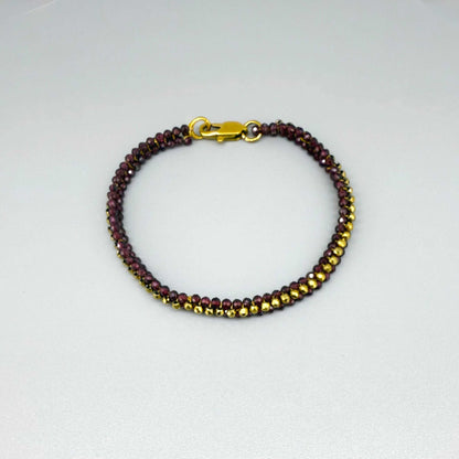 18 cm beaded bracelet made of wine-red garnet and gold-toned hematite with a lobster clasp, displayed on a light background.