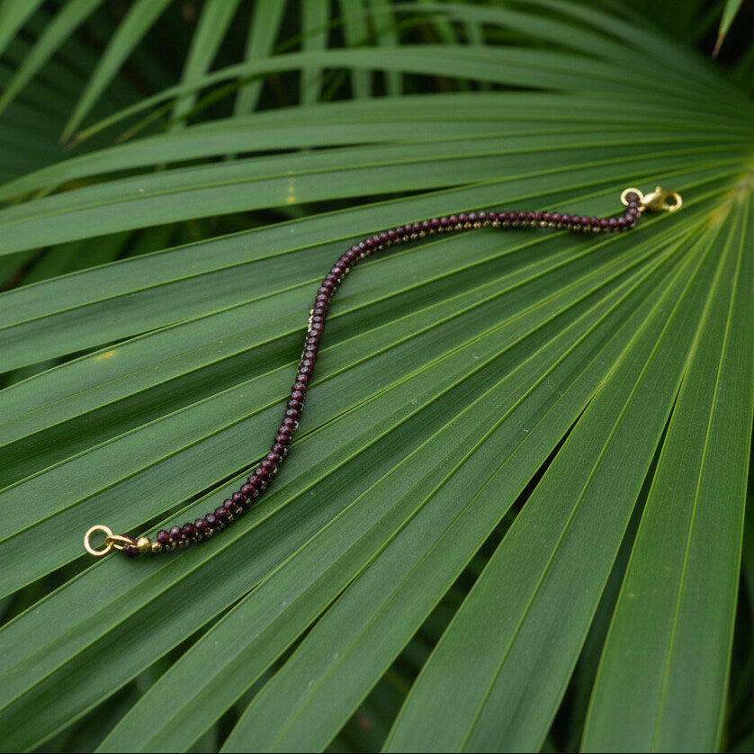 18 cm beaded bracelet made of wine-red garnet and gold-toned hematite with a lobster clasp, displayed on a light background.