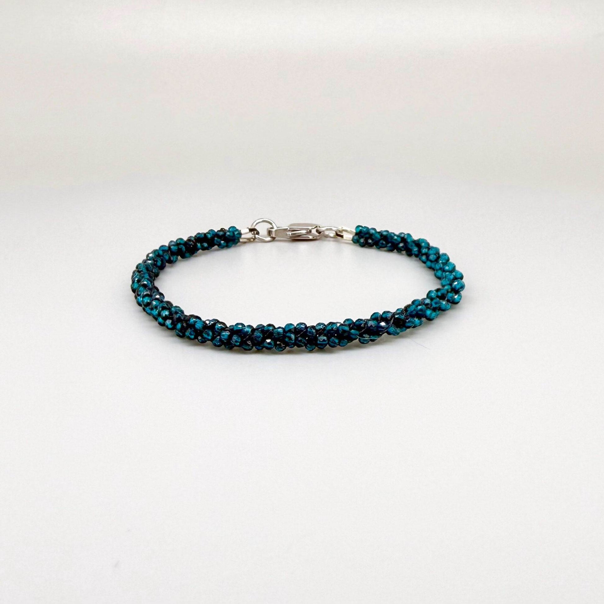 18 cm bracelet made from faceted deep teal apatite beads with a lobster clasp, shown on a light background.