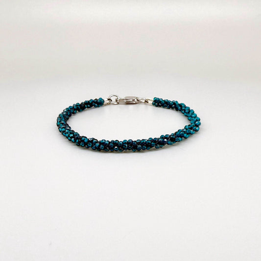 18 cm bracelet made from faceted deep teal apatite beads with a lobster clasp, shown on a light background.