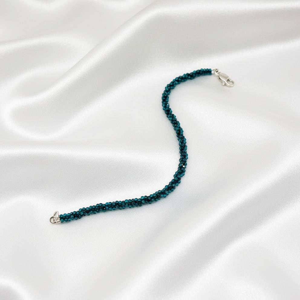 18 cm bracelet made from faceted deep teal apatite beads with a lobster clasp, shown on a light background.