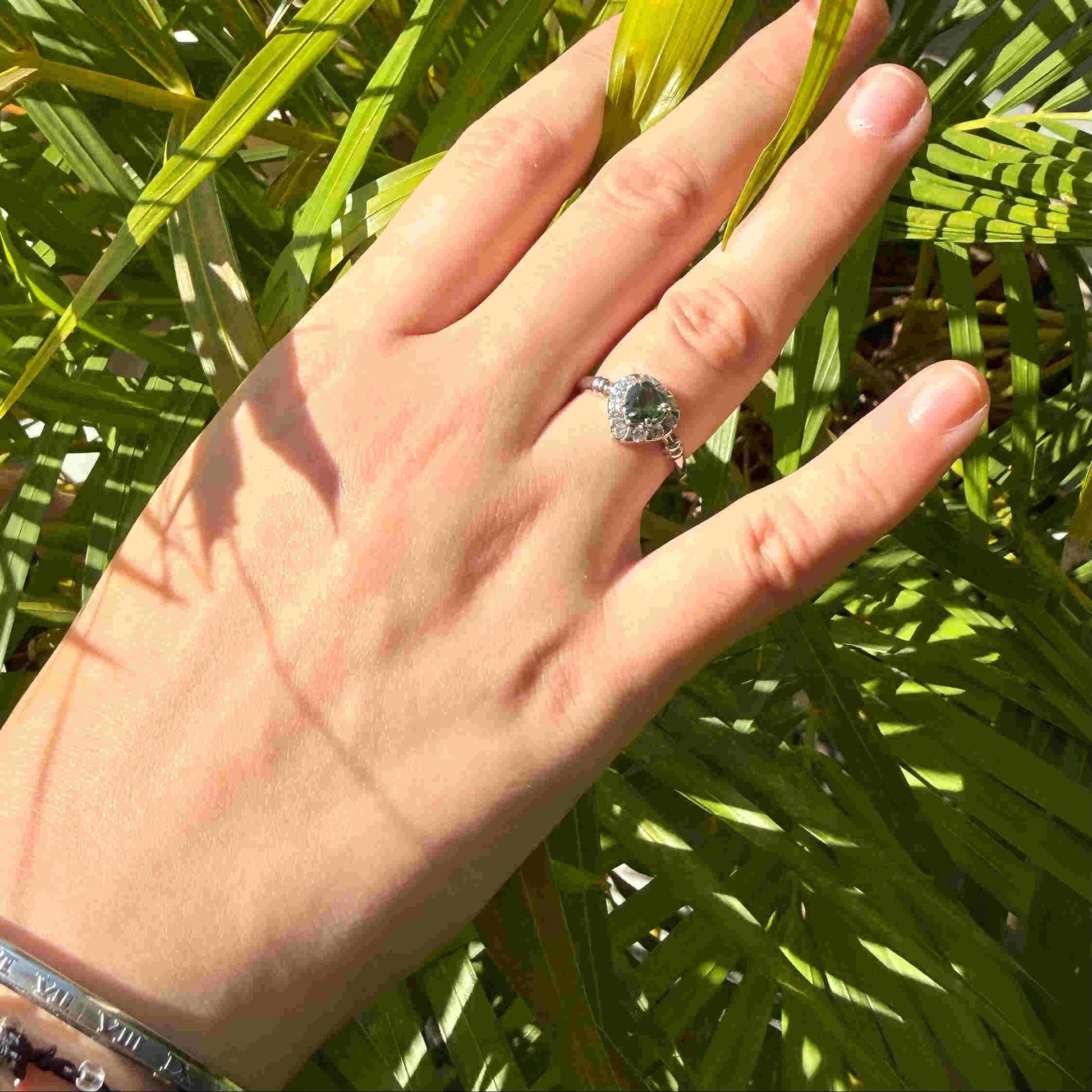 White gold plated silver solitaire ring with heart-shaped green sapphire and cubic zirconia centerpiece.