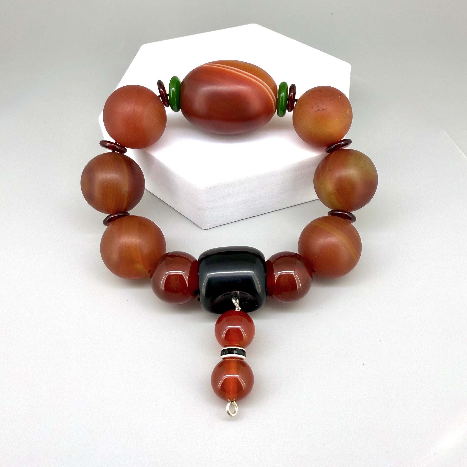 Carnelian and agate beaded bracelet, 20cm, red-orange gemstone beads with large black square bead on elastic stretch band.