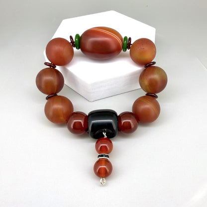 Carnelian and agate beaded bracelet, 20cm, red-orange gemstone beads with large black square bead on elastic stretch band.