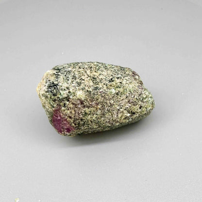 Natural ruby in matrix rough stone with grey-greenish host rock and vivid pink ruby core, uncut specimen.
