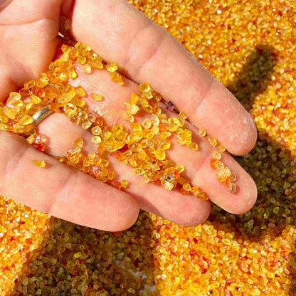 Natural sapphire rough with warm yellow-orange hues and subtle color variation, uncut corundum photographed on neutral background.