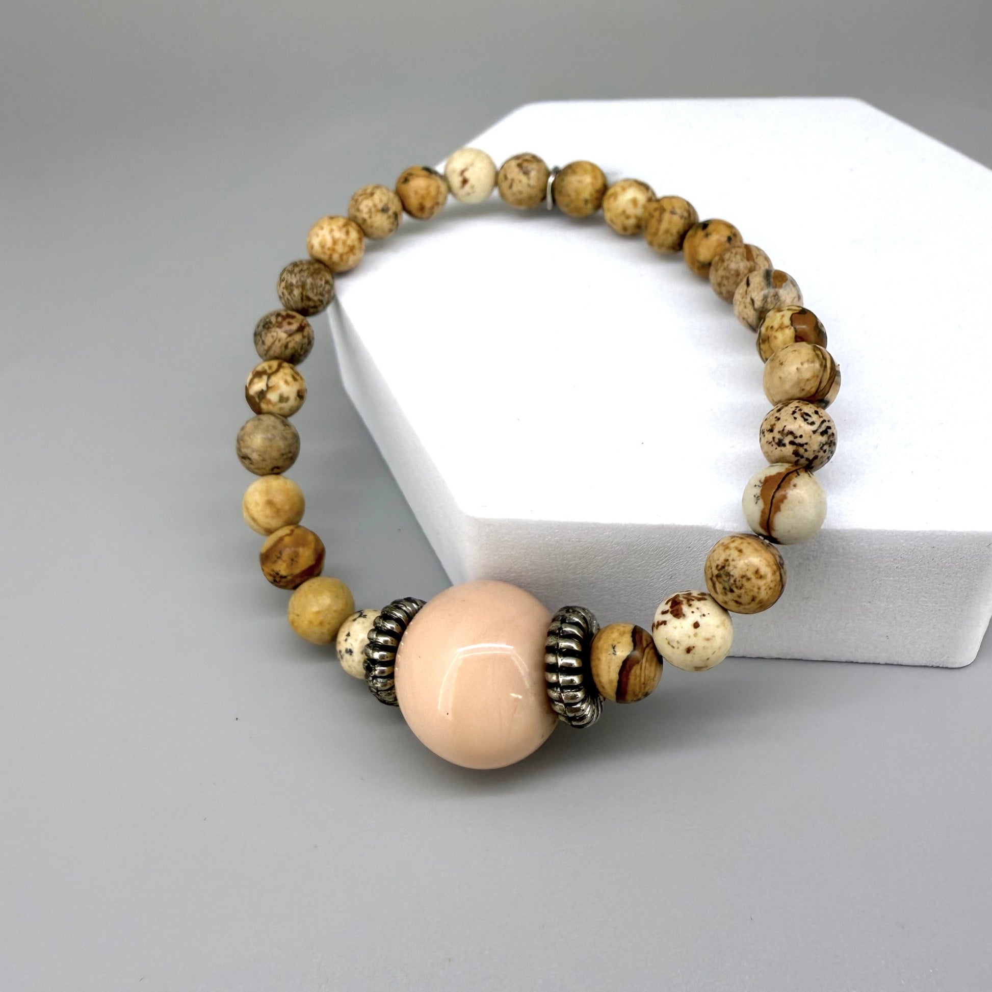 Jasper beaded bracelet, 18cm, light earthy tones with peach-colored focal bead on elastic stretch band.
