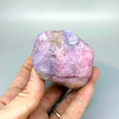 Natural ruby rough stone in lilac to purplish-pink tones, uncut corundum specimen.