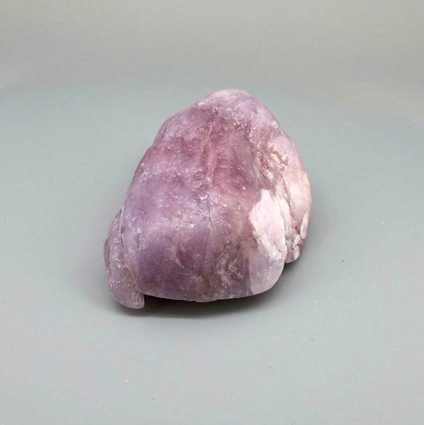 Natural ruby rough stone in soft pink to pale rose tones, uncut corundum specimen photographed on neutral background.