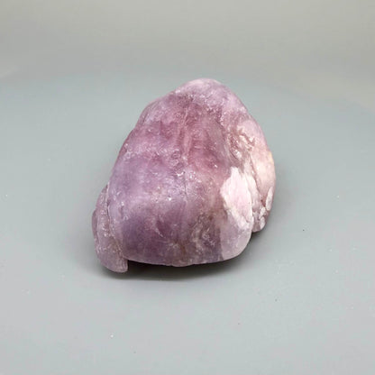 Natural ruby rough stone in soft pink to pale rose tones, uncut corundum specimen photographed on neutral background.