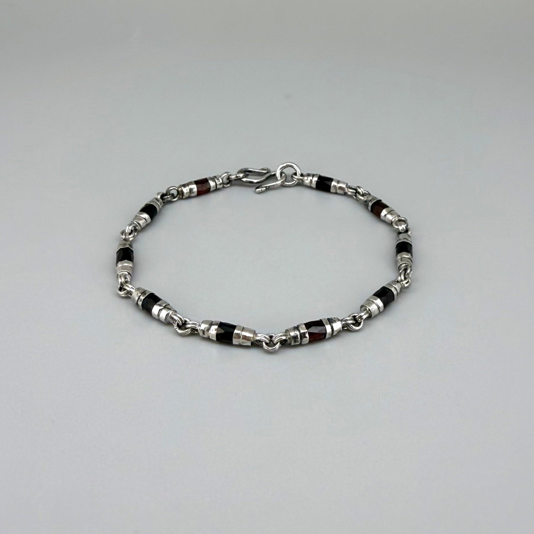 Garnet Pyrope bracelet in sterling silver with white gold plating, elegant design on neutral background
