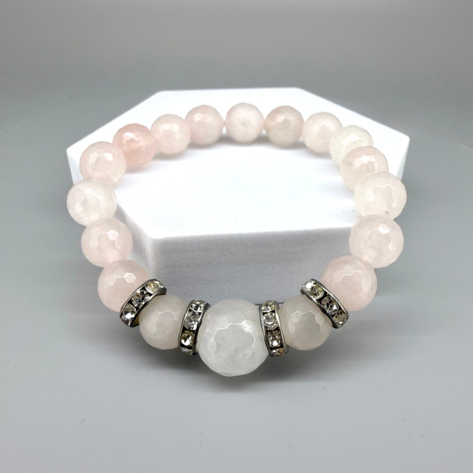 Rose quartz beaded bracelet, 18cm, light pink gemstone beads with larger central bead and decorative metal accents on elastic stretch band.