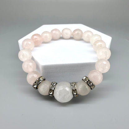Rose quartz beaded bracelet, 18cm, light pink gemstone beads with larger central bead and decorative metal accents on elastic stretch band.
