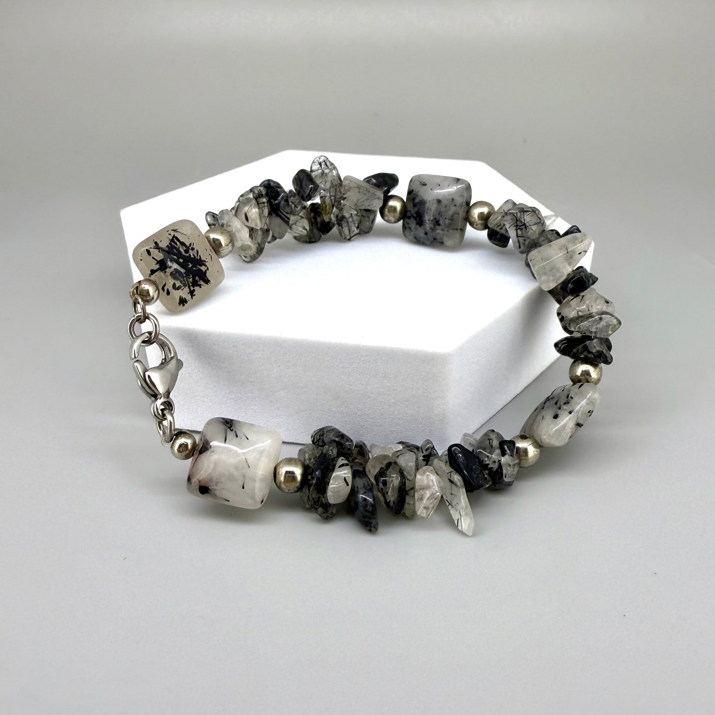 Rutilated quartz bracelet, 19cm, irregular nugget beads in grey, black, and white tones with metal spacers and clasp.