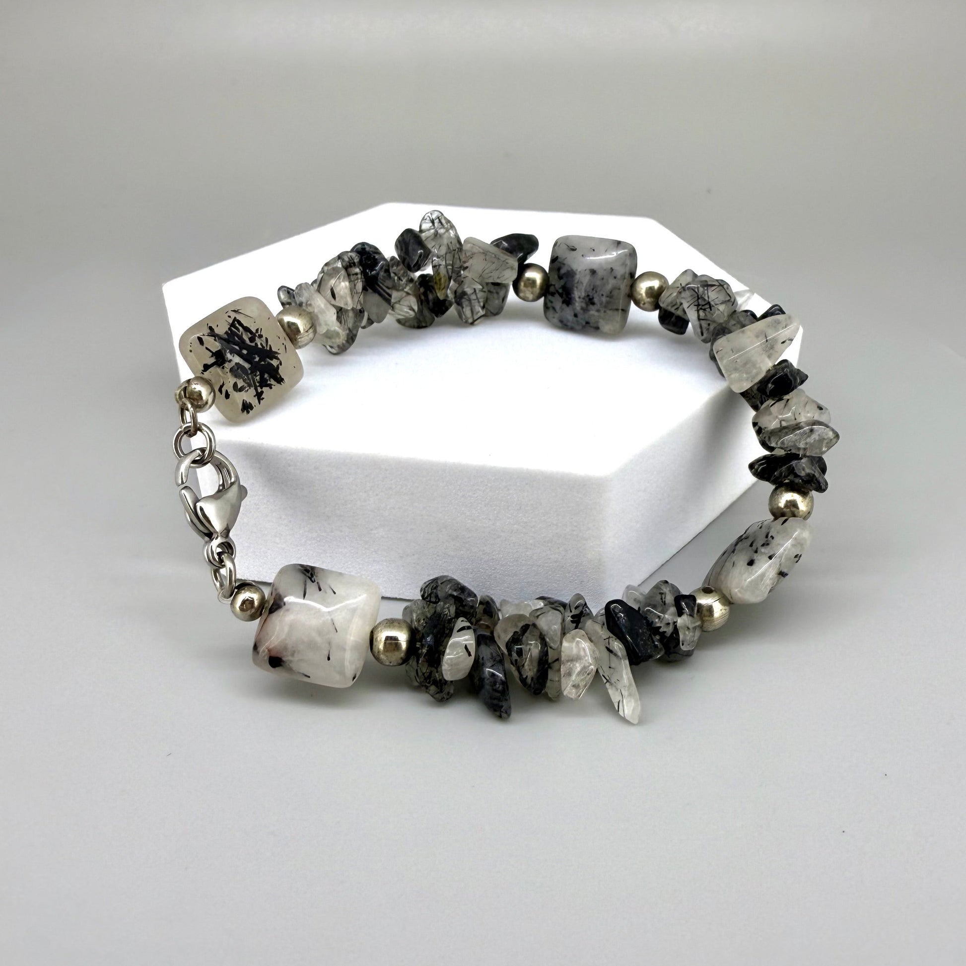 Rutilated quartz bracelet, 19cm, irregular nugget beads in grey, black, and white tones with metal spacers and clasp.