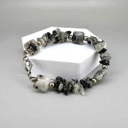Rutilated quartz bracelet, 19cm, irregular nugget beads in grey, black, and white tones with metal spacers and clasp.