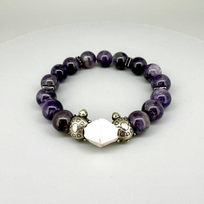 Amethyst beaded bracelet, 18cm, violet gemstone beads with pink-white accent stone and two metal turtle beads on elastic stretch band.