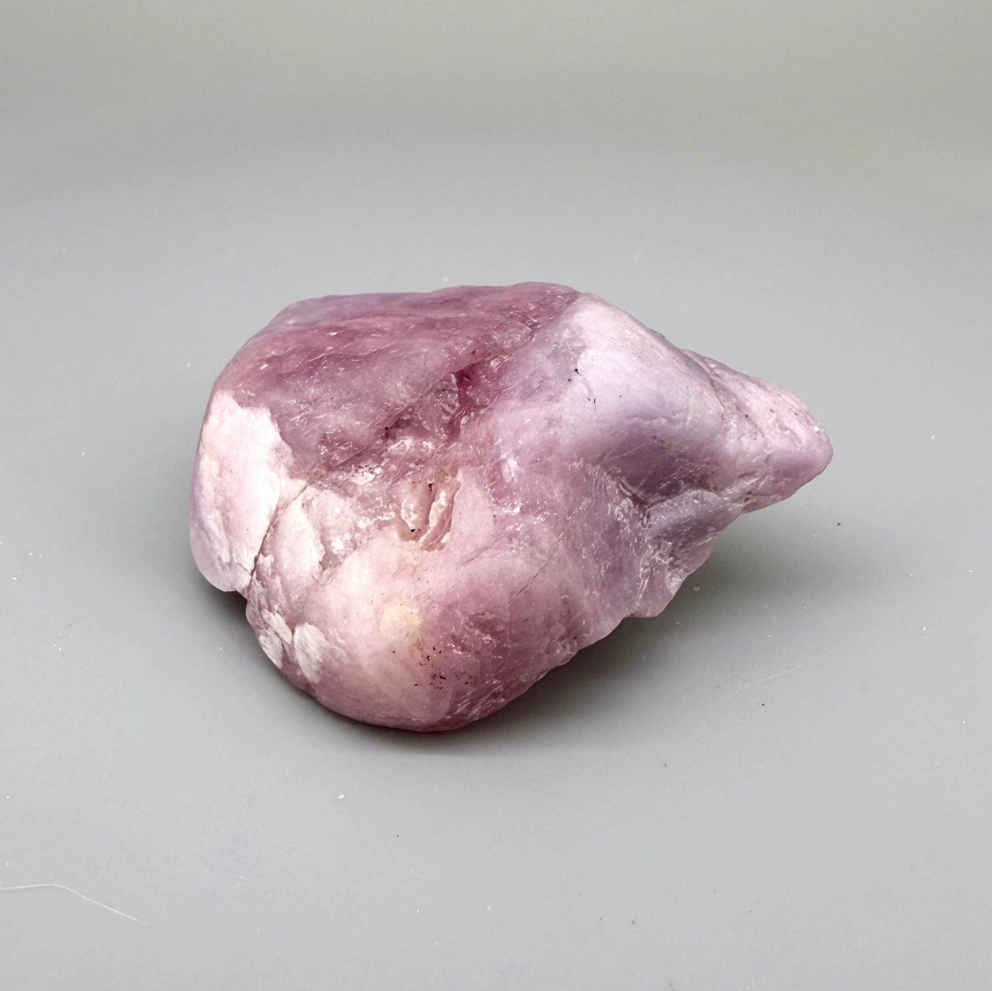 Natural ruby rough stone in soft pink to pale rose tones, uncut corundum specimen photographed on neutral background.