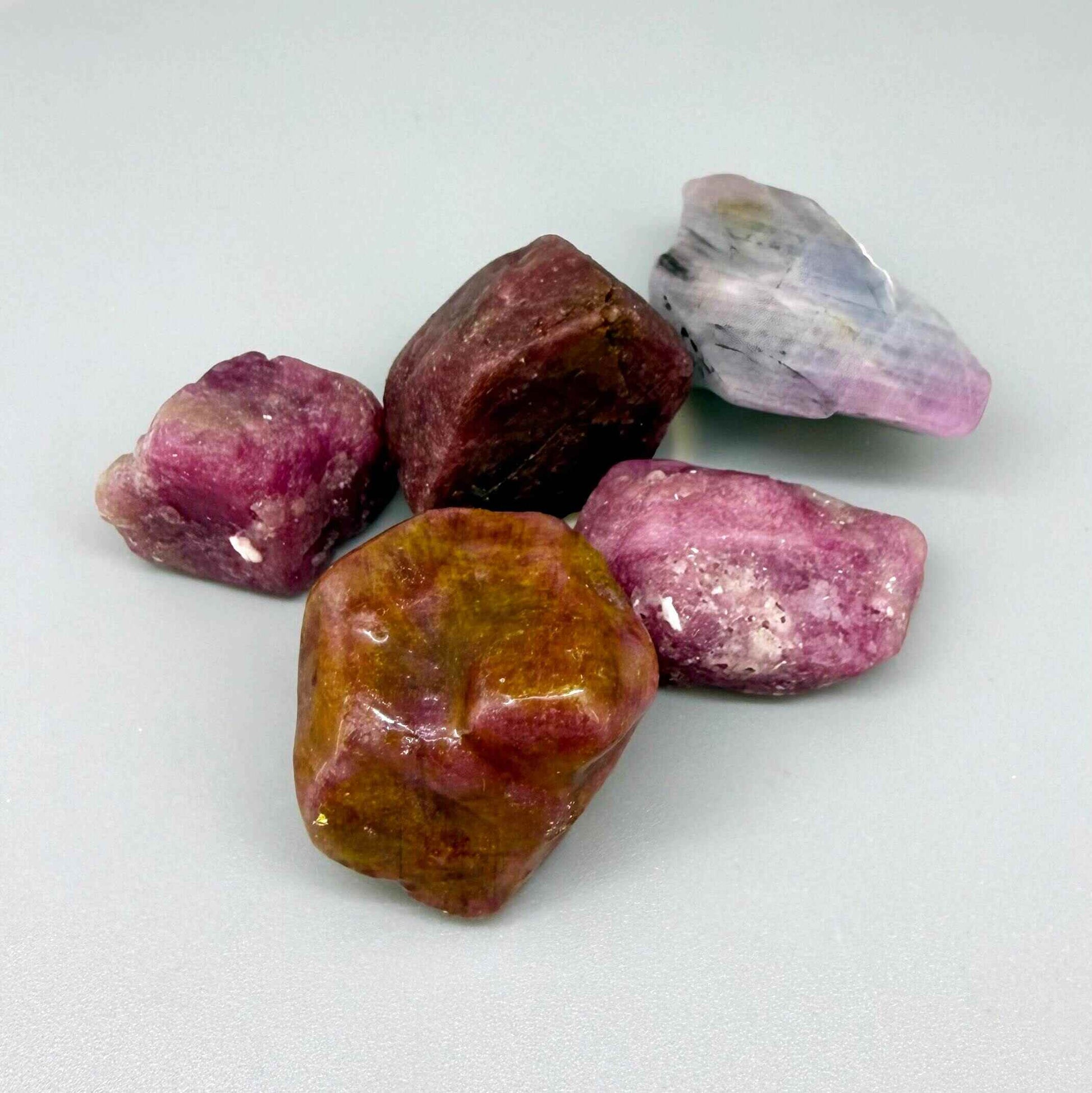 Natural ruby rough lot with pink to purplish-pink and raspberry tones, uncut corundum stones.