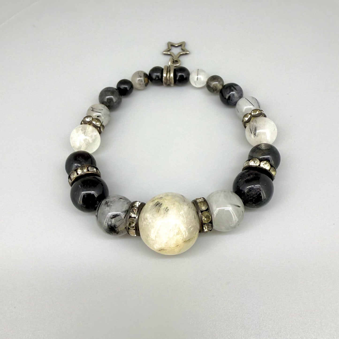 Rutilated quartz beaded bracelet, 18cm, black rutile inclusions with larger light bead and star charm on elastic stretch band.