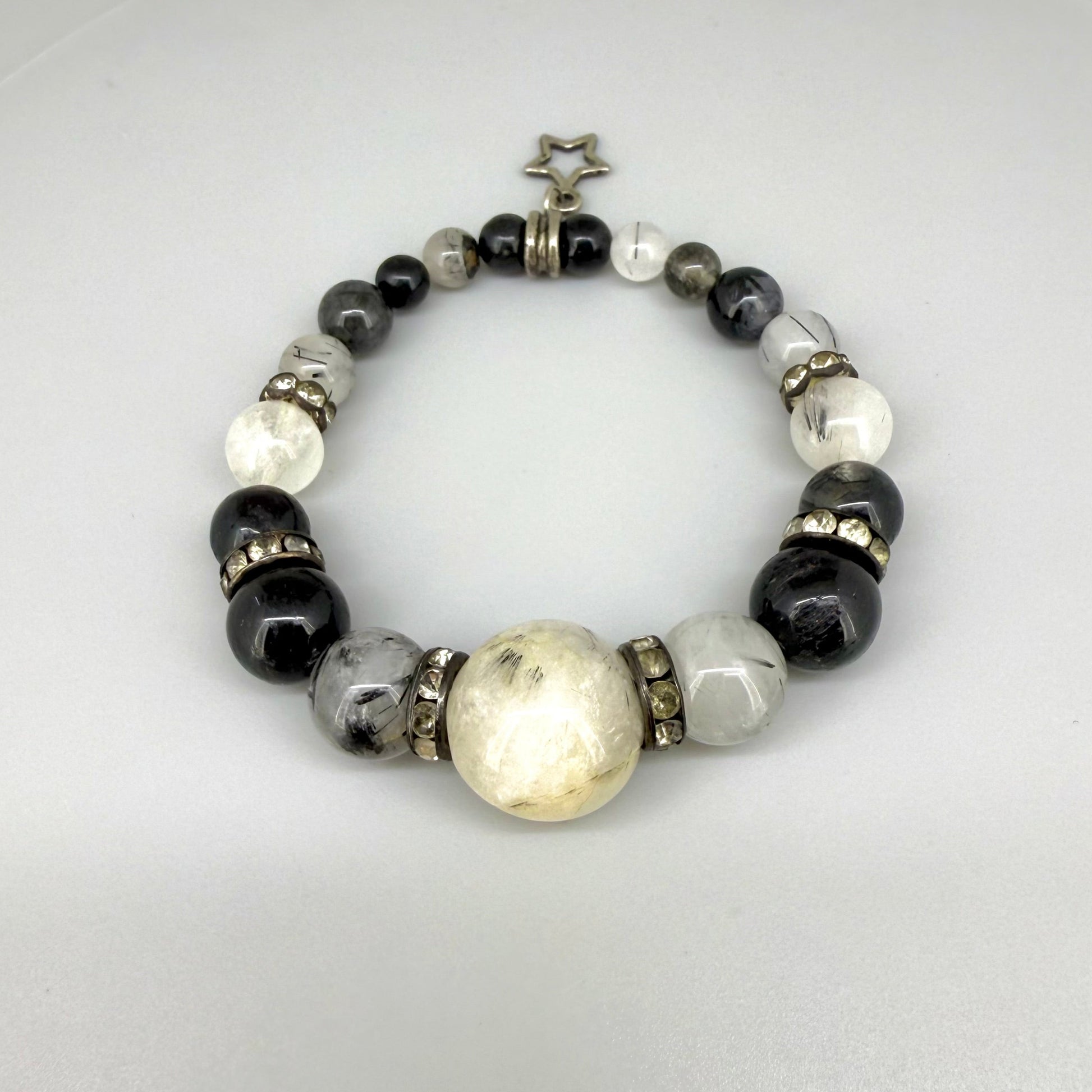 Rutilated quartz beaded bracelet, 18cm, black rutile inclusions with larger light bead and star charm on elastic stretch band.
