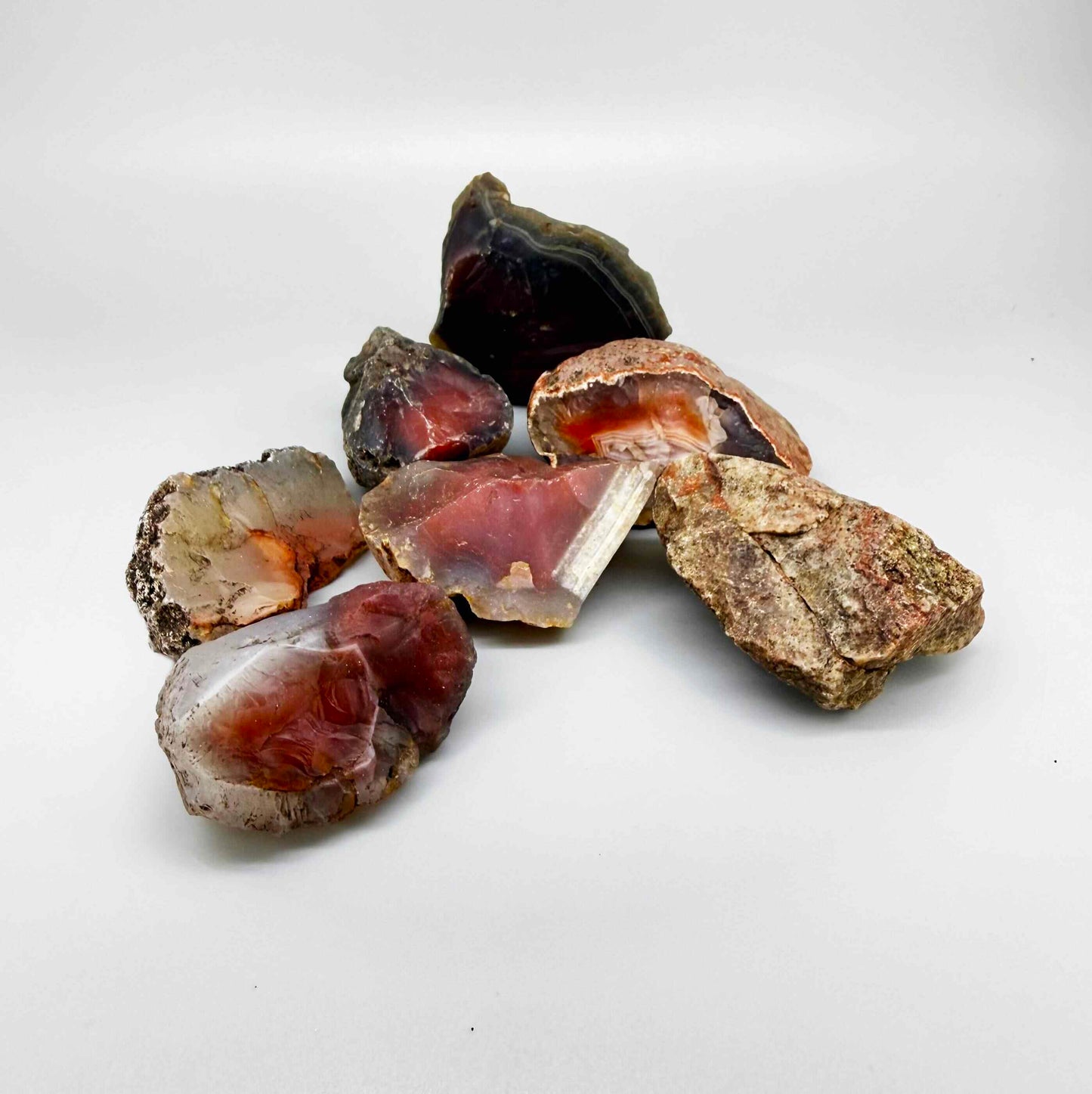 Natural chalcedony / carnelian rough lot in warm orange and red hues, uncut quartz material.