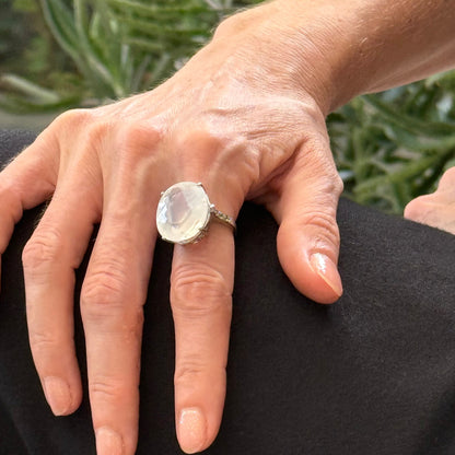 White quartz and sapphire ring in white gold plated sterling silver, featuring a faceted clear gemstone framed by blue sapphires, elegant and refined design.
