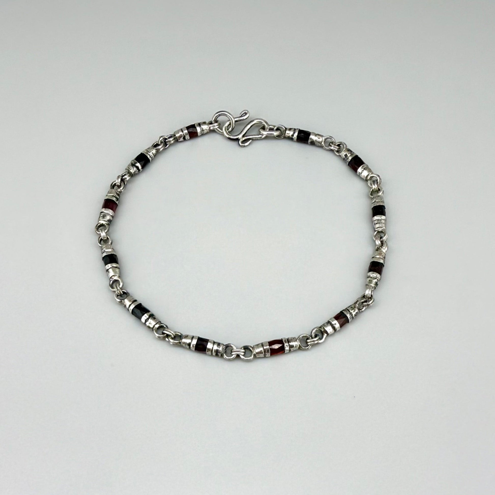 Garnet Pyrope bracelet in sterling silver with white gold plating, elegant design on neutral background