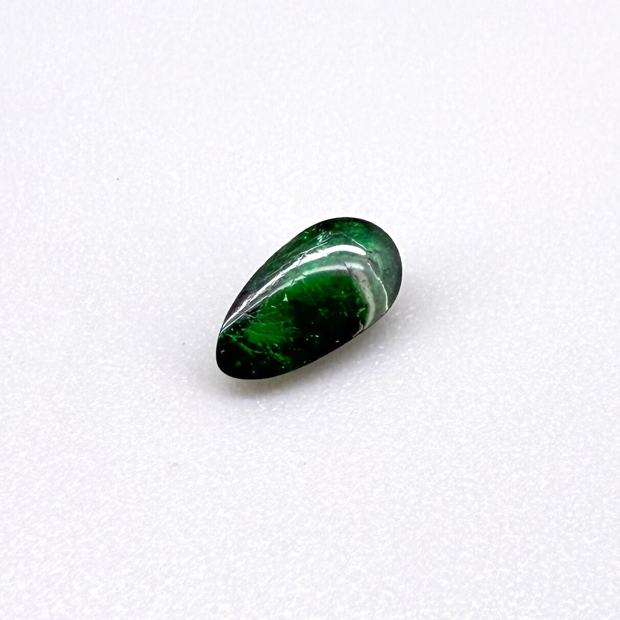0.67 ct natural untreated emerald from Zambia, one side polished and the other cabochon-shaped.