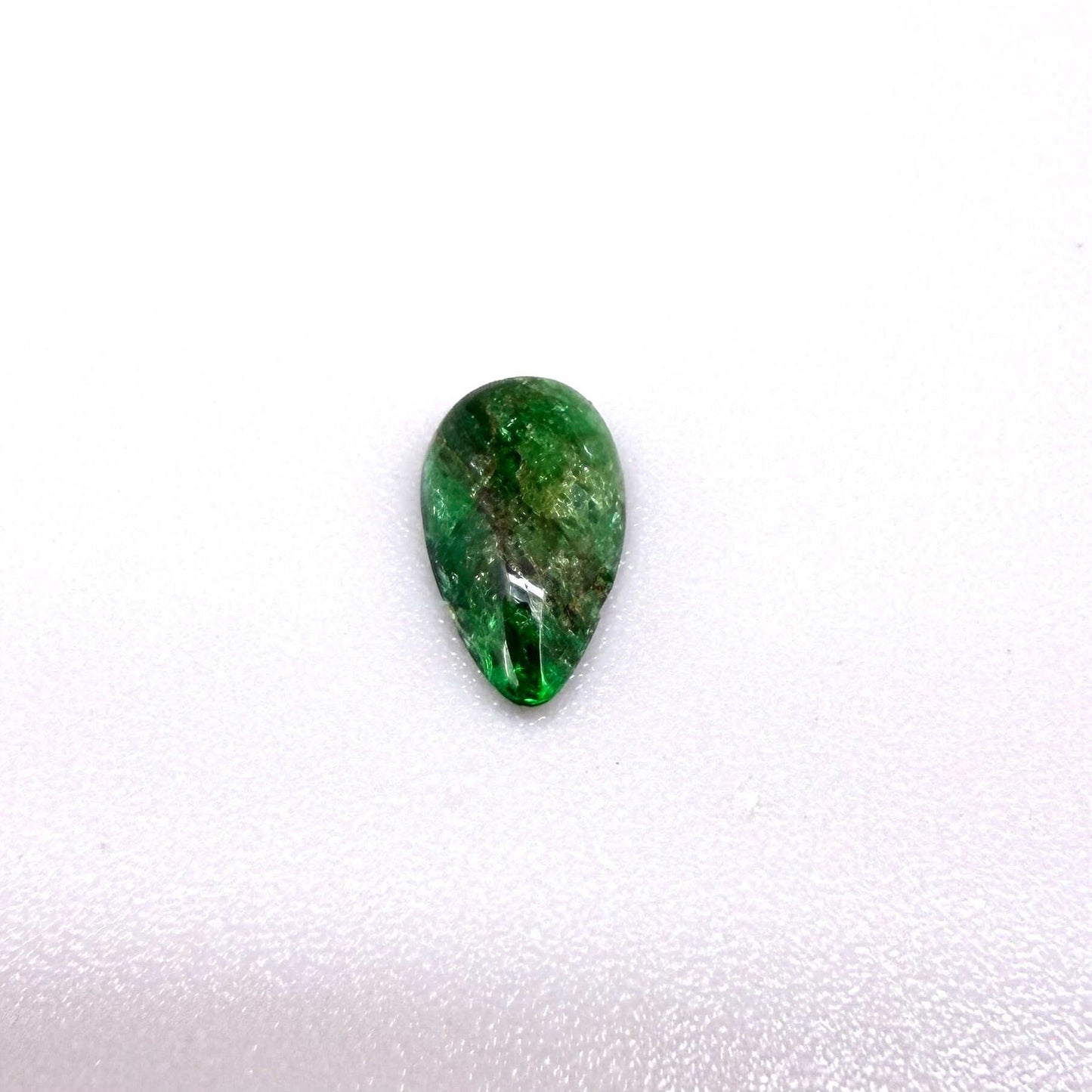 0.9 ct natural untreated emerald from Zambia, one side polished and the other cabochon-shaped.