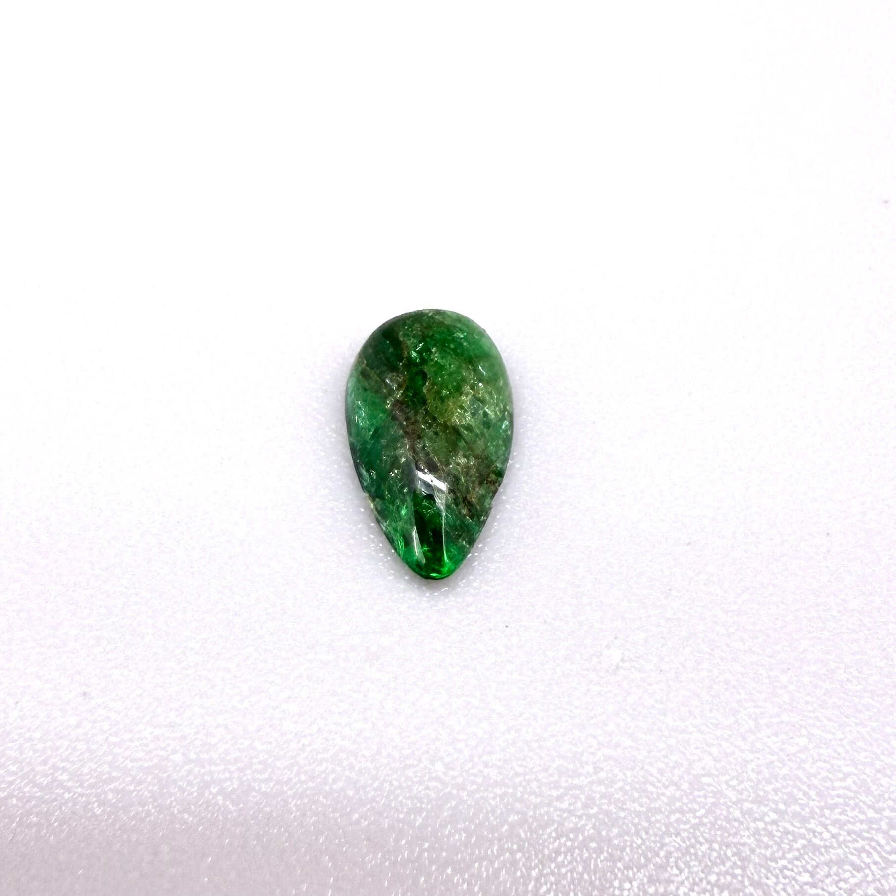 0.9 ct natural untreated emerald from Zambia, one side polished and the other cabochon-shaped.