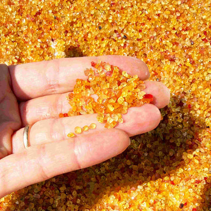 Natural sapphire rough with warm yellow-orange hues and subtle color variation, uncut corundum photographed on neutral background.