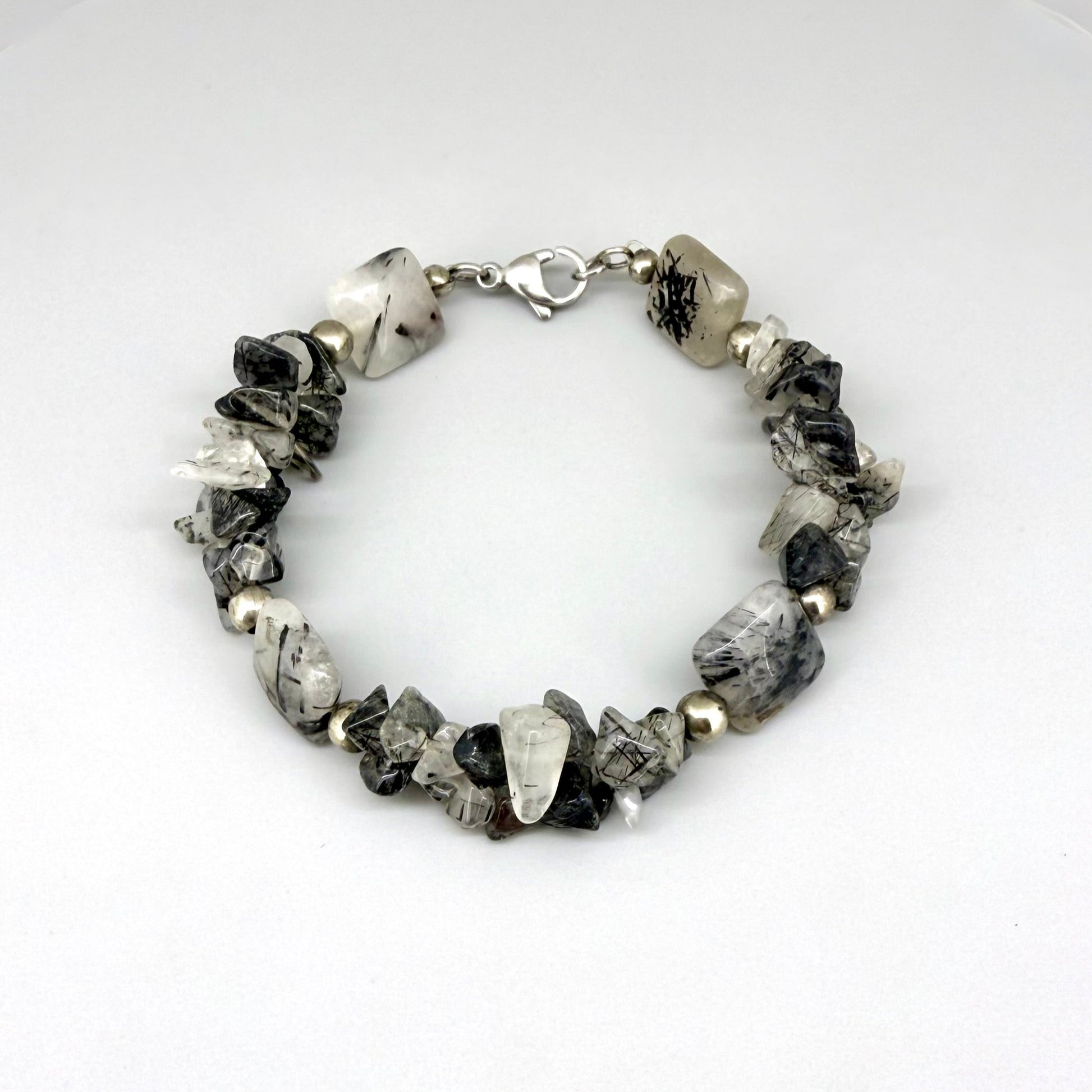 Rutilated quartz bracelet, 19cm, irregular nugget beads in grey, black, and white tones with metal spacers and clasp.
