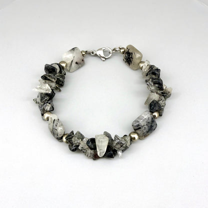 Rutilated quartz bracelet, 19cm, irregular nugget beads in grey, black, and white tones with metal spacers and clasp.
