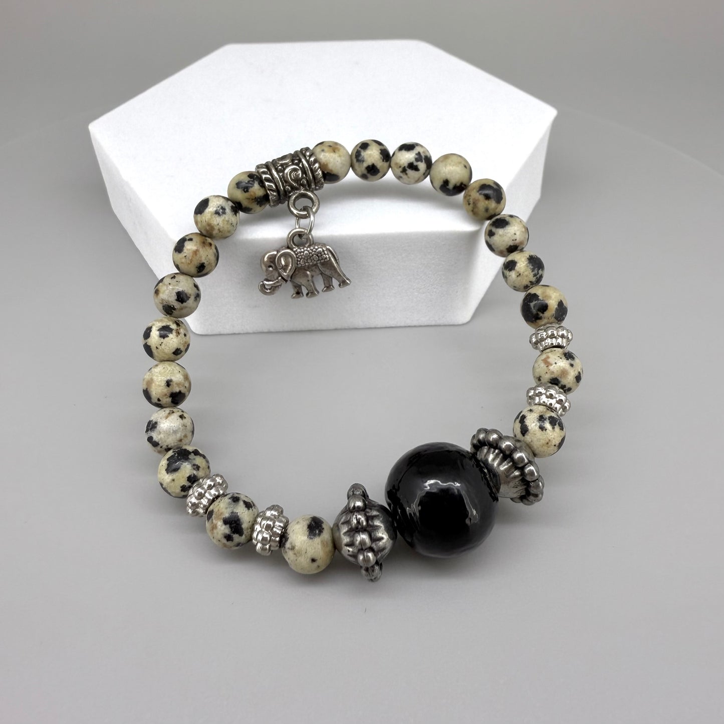 Dalmatian jasper beaded bracelet, 17cm, cream with black speckled gemstone beads and one large black accent bead on elastic stretch band.