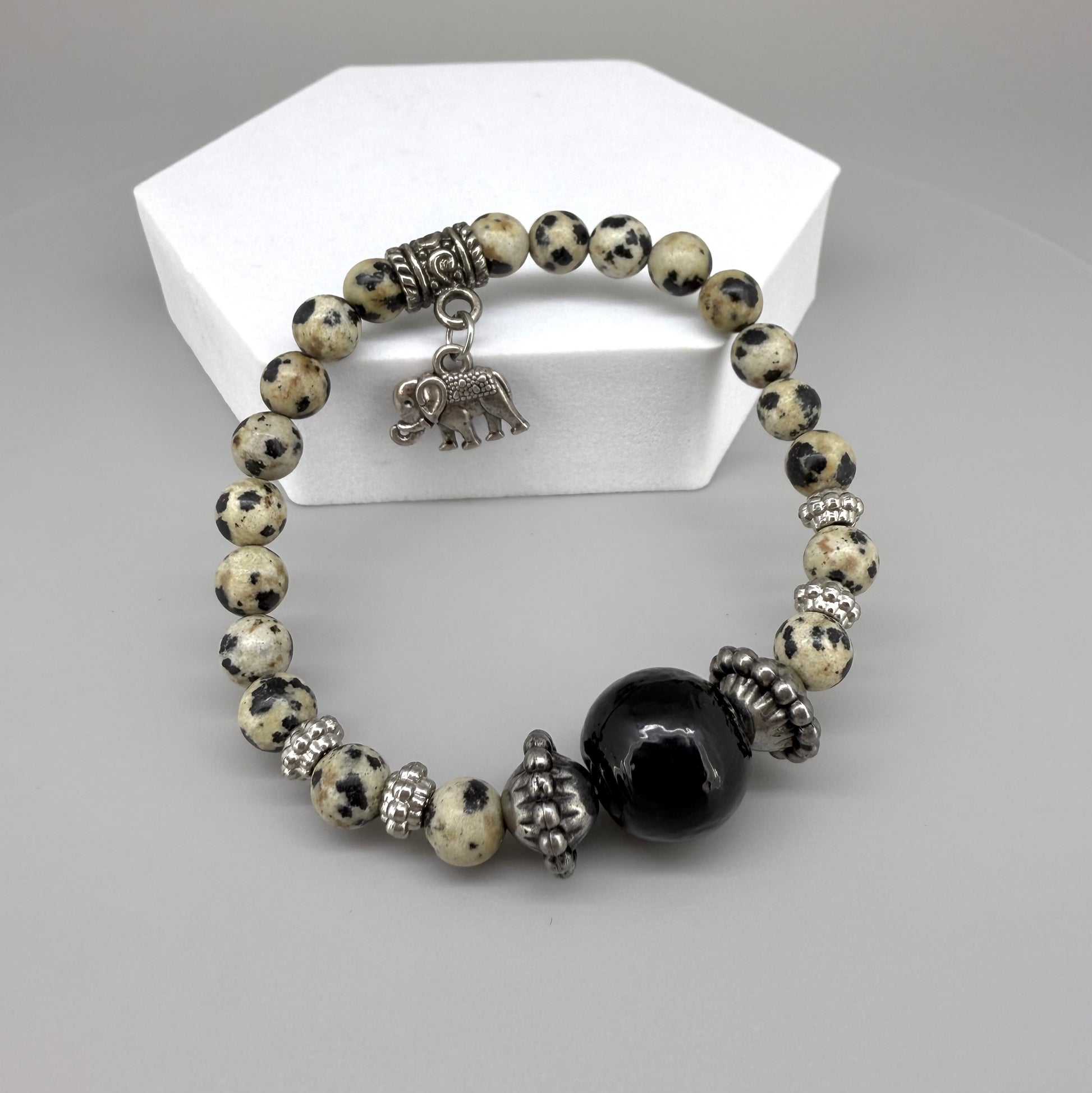 Dalmatian jasper beaded bracelet, 17cm, cream with black speckled gemstone beads and one large black accent bead on elastic stretch band.