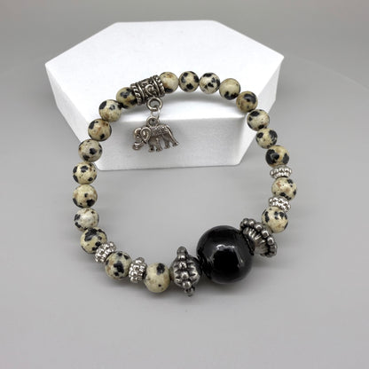Dalmatian jasper beaded bracelet, 17cm, cream with black speckled gemstone beads and one large black accent bead on elastic stretch band.