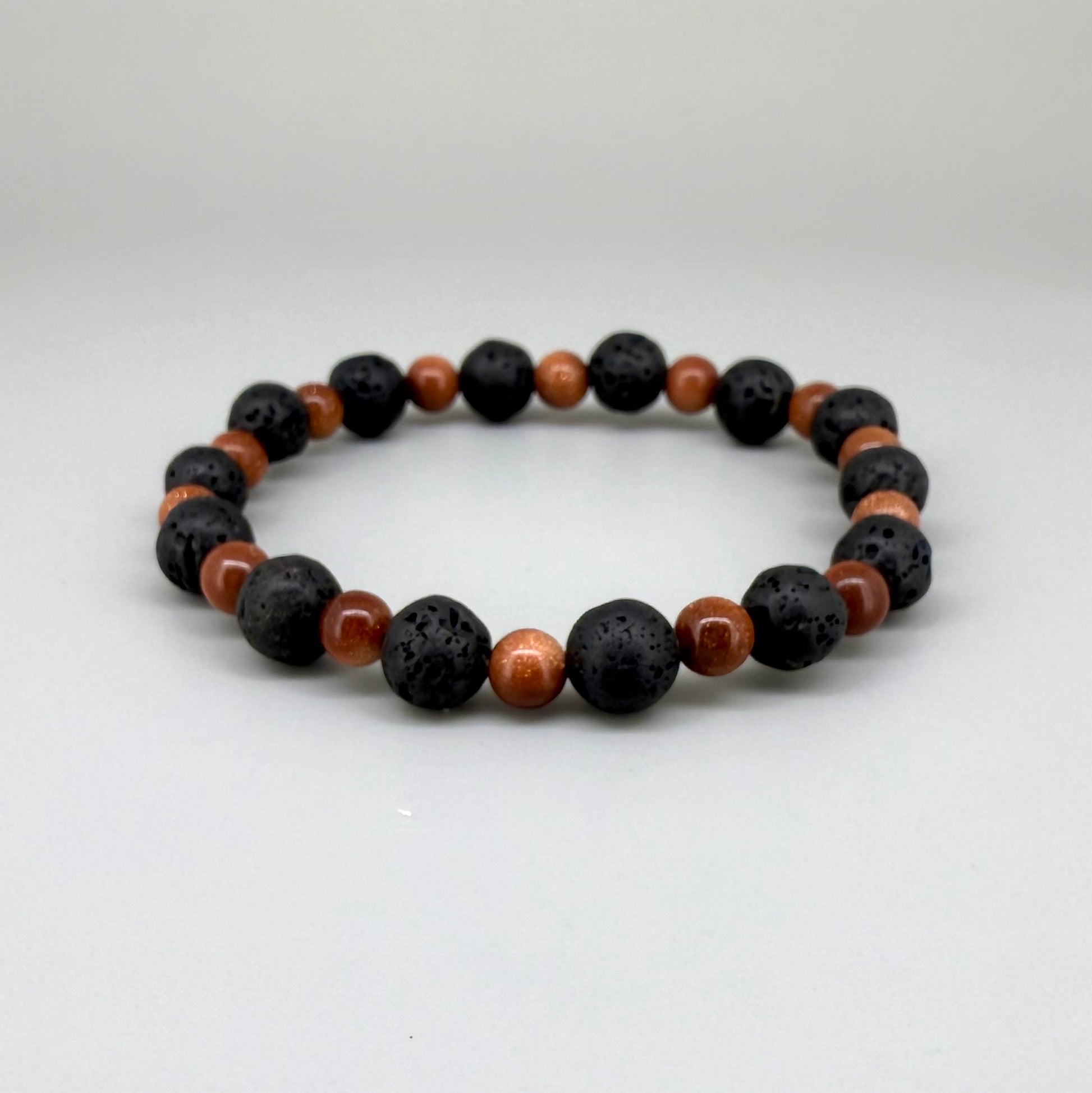Lava and goldstone beaded bracelet, 18cm, alternating matte black lava beads and smaller shimmering golden-brown man-made goldstone beads on elastic stretch band.
