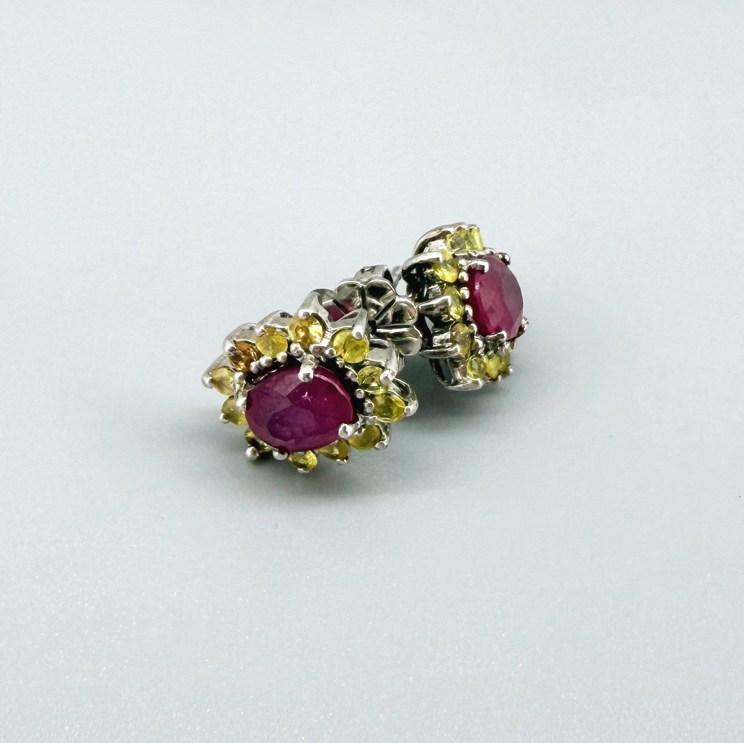 Ruby and yellow sapphire stud earrings in white gold plated sterling silver with butterfly backs.