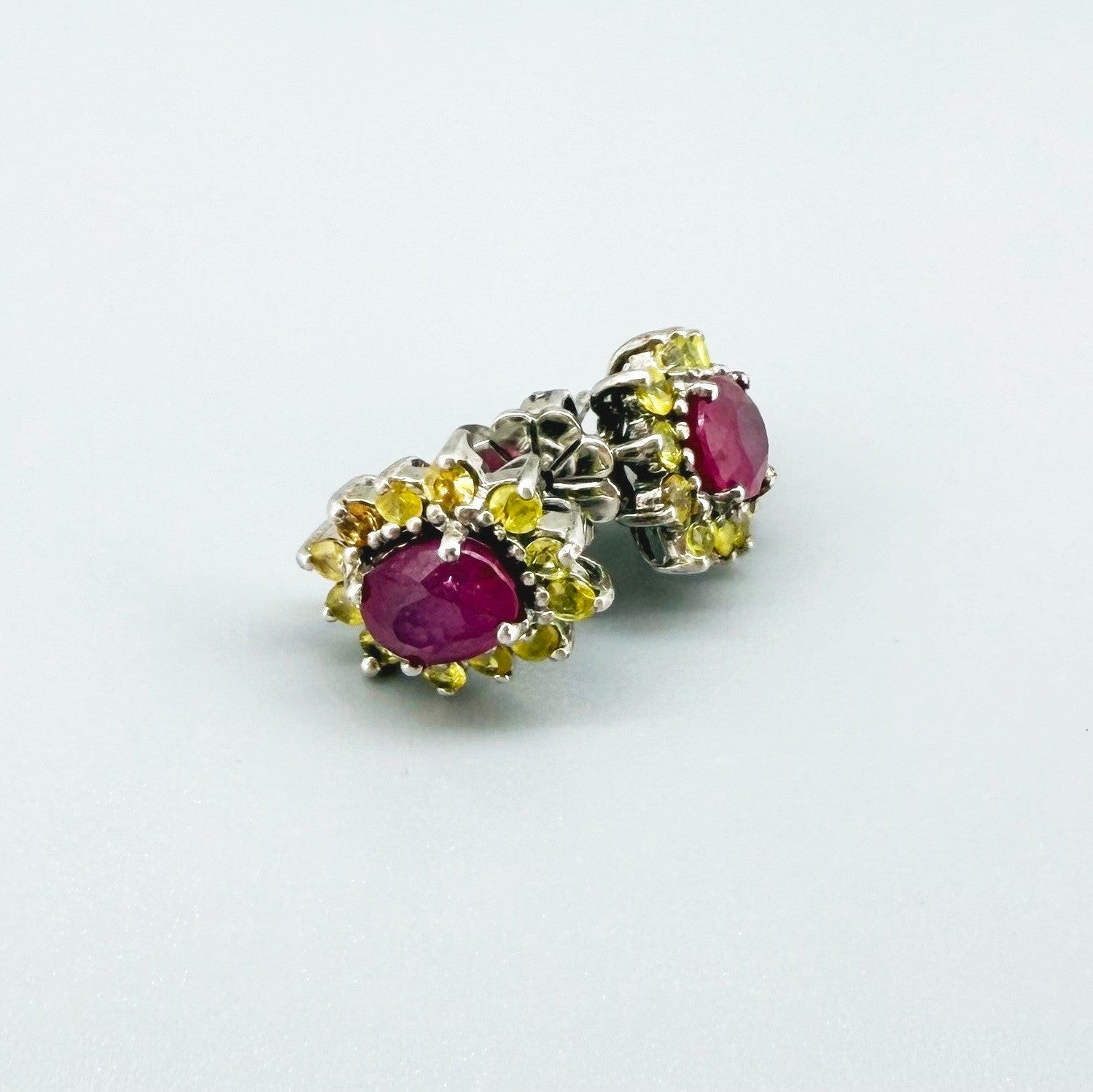 Ruby and yellow sapphire stud earrings in white gold plated sterling silver with butterfly backs.